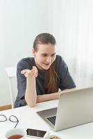 Girl listens or looks at information on computer with disbelief. Skeptical expression. Fake news. photo