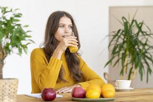 Young girl drinking orange juice, smiling. Beautiful woman with long hair photo