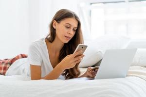 Young woman shopping online, entering code from SMS message on mobile phone, security photo