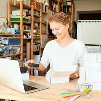 Happy owner of local business. Female entrepreneur collecting and packing gifts photo