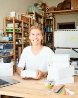 Happy owner of local business. Female entrepreneur collecting and packing gifts photo