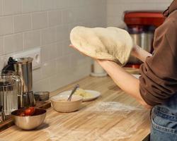 Faceless woman kneading dough on kitchen table at home, apartment. Homemade food photo