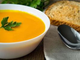 white bowl of pumpkin soup decorated with parsley greens photo