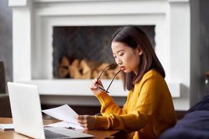 Asian woman working at home looking at documents. Beautiful Japanese female