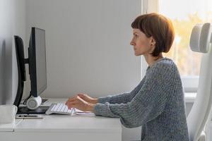 postura correcta y posición sentada en el escritorio de la computadora a una distancia segura del monitor foto