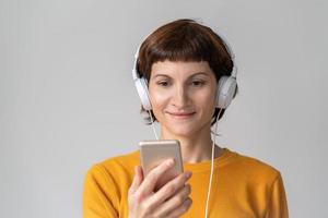 Middle-aged happy woman looking at phone, listening to music. Mature female. photo