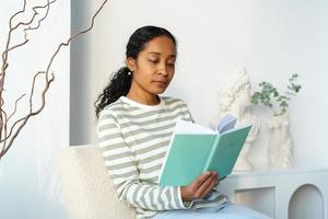 mujer afroamericana leyendo pacíficamente un libro en su tiempo libre. desintoxicación digital. estilo de vida lento foto
