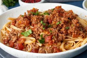 Pasta Bolognese Linguine with mincemeat and tomatoes, parmesan cheese. Side view, close up photo