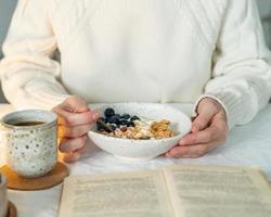 Reading book and eating healthy holiday winter breakfast with granola photo