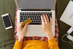 Online shopping concept. Unrecognizable woman sitting at bed, paying for purchases by credit card photo