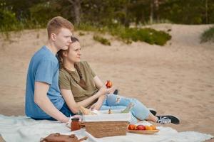 Teen couple resting on blanket during picnic on beach