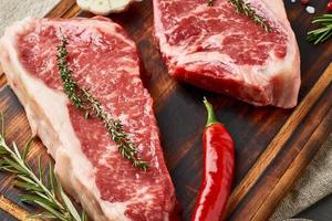 Two big whole piece of raw beef meat, striploin on wooden cutting board, macro, close up photo