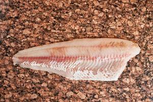 Fresh raw pike perch fish fillet on marble dark brown table. Top view photo