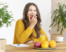 Young girl bitting red apple, smiling. Beautiful woman with long hair photo