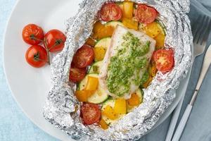 cena de paquete de aluminio con pescado blanco. lomo de bacalao al horno, lucioperca con verduras foto