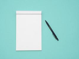 Top view workspace mockup on aqua background with open notebook and pen