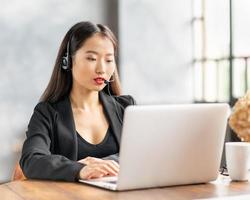 Asian businesswoman in headset speaking by conference call and video chat