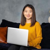 mujer de negocios asiática que trabaja en la computadora portátil en el sofá. empresaria japonesa trabaja en casa foto