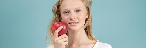 pancarta de largo ancho con retrato de una joven sonriente con manzana roja. cara fresca foto