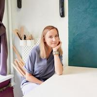 Business woman sitting at table and smiling in ceramic workshop. Young businesswoman at pottery photo