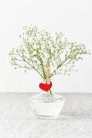 Valentine's Day. Delicate white flowers in vase. Red felt heart - symbol of love