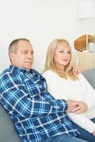 Waist portrait of mature couple in home interior on sofa. Handsome man and middle age woman photo