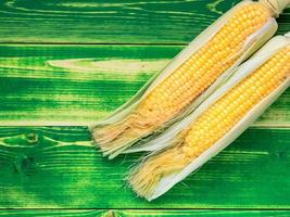 fresh juicy corn on the cob on a bright green wooden background. photo