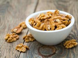 white cups with walnut, bowls with handful of nuts on grey wooden background. photo