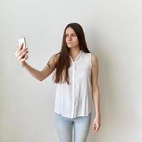 Calm, emotionless woman takes selfie on cell phone. Serious, unflappable female photo