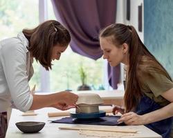 Student observing work of master of clay modeling with concentration photo