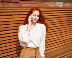 Red-haired woman talking on cell phone. Beautiful stylish fashion model photo