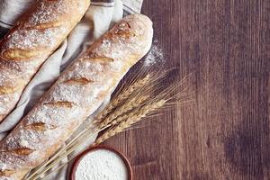 baguette de pan crujiente casero recién horneado. dos panes en toalla de lino foto