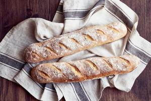 baguette francesa crujiente casera recién horneada. dos panes en toalla de lino foto