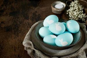 Unusual Easter on dark old background. Ceramic brown bowl with blue eggs. photo