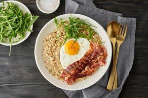 Oatmeal, fried egg and fried bacon. Balance of proteins, fats, carbohydrates. Close up photo