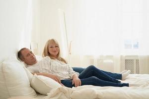 Full length portrait of mature couple in home interior on sofa photo