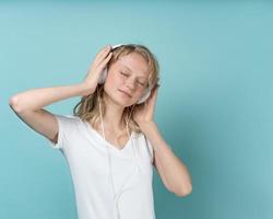 Portrait of young woman listening music via headphones on color neutral tone Aqua Menthe