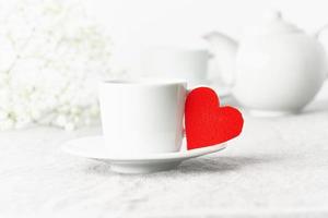 Día de San Valentín. Desayuno matutino para dos con té y flores. corazón de fieltro rojo es símbolo de los amantes foto