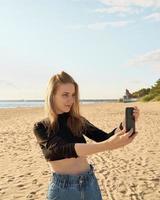 Beautiful woman taking selfie on ocean or sea coastline in sunny day photo