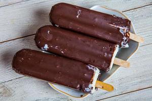 Melting Ice Cream Chocolate Bar Close-up. Ice cream covered with chocolate on wooden background photo