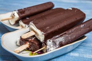 primer plano de barra de chocolate de helado de fusión. helado cubierto con chocolate sobre fondo de madera foto