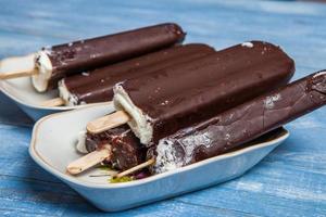 Melting Ice Cream Chocolate Bar Close-up. Ice cream covered with chocolate on wooden background photo