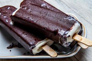 Melting Ice Cream Chocolate Bar Close-up. Ice cream covered with chocolate on wooden background photo