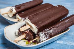 Melting Ice Cream Chocolate Bar Close-up. Ice cream covered with chocolate on wooden background photo