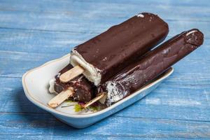 primer plano de barra de chocolate de helado de fusión. helado cubierto con chocolate sobre fondo de madera foto