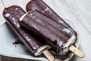 Melting Ice Cream Chocolate Bar Close-up. Ice cream covered with chocolate on wooden background photo