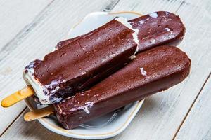 Melting Ice Cream Chocolate Bar Close-up. Ice cream covered with chocolate on wooden background photo