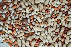 Assorted nuts for a background Almond, walnut,cashew, pistachios, hazelnuts, peanuts, Macadamia Collection of different varieties of nuts. Composition with dried fruits Healthy food. Organic. photo