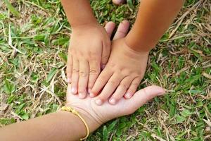 Children's hands and mother's hands touch the grass and the earth. photo