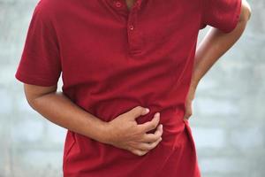 man covers his stomach that is suffering from gastritis. photo